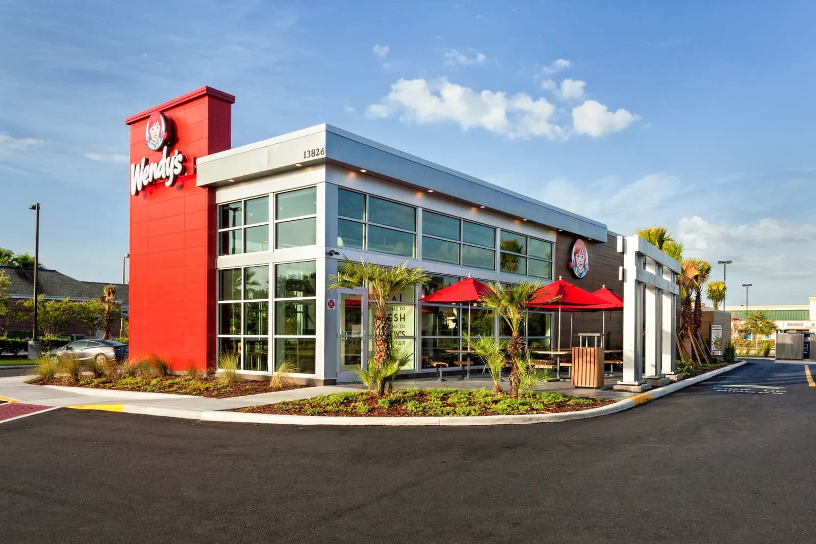Exterior of a Wendy's restaurant with its red sign tower and glass frontage on a sunny day